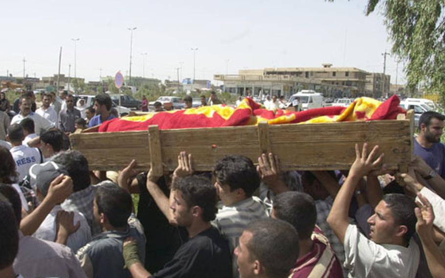 Angry residents of Fallujah, Iraq, surround the casket Saturday of the first of eight Iraqi Police officers to be buried after an accidental shootout with American soldiers on Friday.