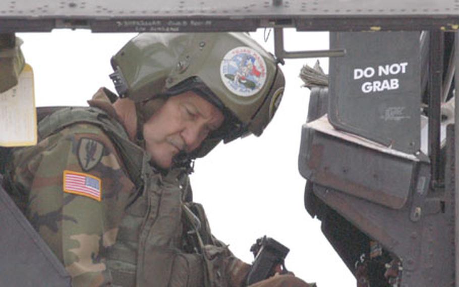 Chief Warrant Officer 4 Duke Russell of Company B, 1st Battalion, 108th Aviation Regiment, prepares for a flight in an Apache helicopter. The love of flying has kept him in the military since the war in Vietnam, through a deployment in Korea and an assignment as an SFOR peacekeeper in Bosnia and Herzegovina. Like five other veteran pilots at Eagle Base, he does not plan to retire before he has to.