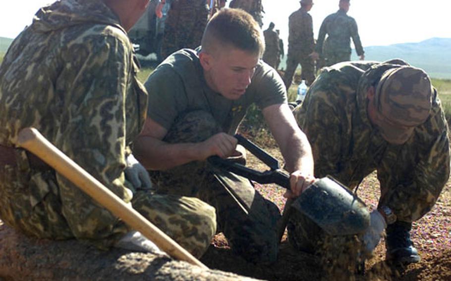 Lance Cpl. Frank L. Whitslar, combat engineer, 9th Engineer Support Battalion, digs next to a Mongolian service member as they prepare to build a log wall during the second phase of training of Khaan Quest &#39;03.