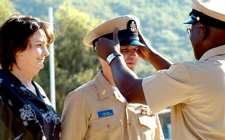 Chief Petty Officer Charles Dennison places the chief&#39;s combination cap on Chief Petty Officer Phillip Brown, whose wife, Gloria, left, just pinned the two chief&#39;s anchors on his collar. Brown is assigned to the Naples, Italy-based Naval Telecommunications Area Master Station European Central.