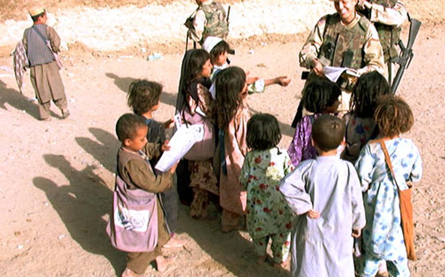 Spc. Janei Worley, of the 308th Tactical Psychological Operations Company, hands out anti-mine leaflets to children Monday in Abdul Hakim Jan Kalay, Afghanistan.