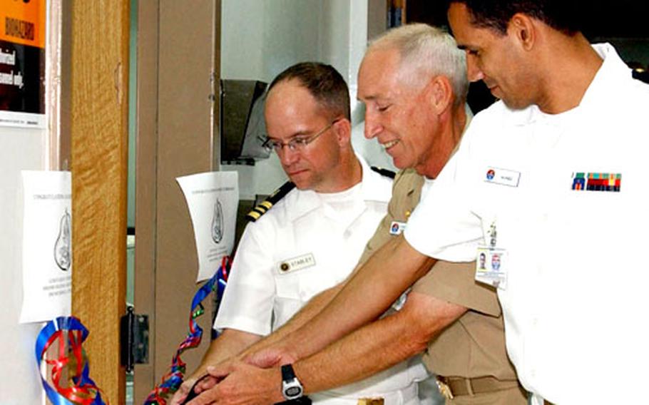 Capt. Denzel Garner, left, and two U.S. Naval Hospital Sigonella medical officers cut a ribbon to celebrate the opening of the new pathology lab on Tuesday.