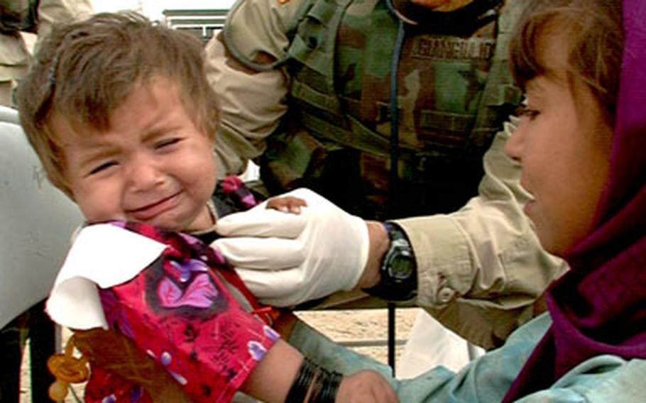 Capt. Louis Giangiulio, a pediatrician, examines an unhappy young patient Tuesday during a civil medical assistance visit to the village of Raibi Kalasha, Afghanistan.