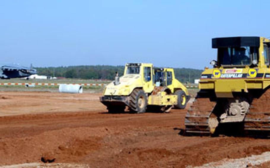 A plane prepares to take off at Ramstein Air Base Wednesday while construction crews work on the runway extension.