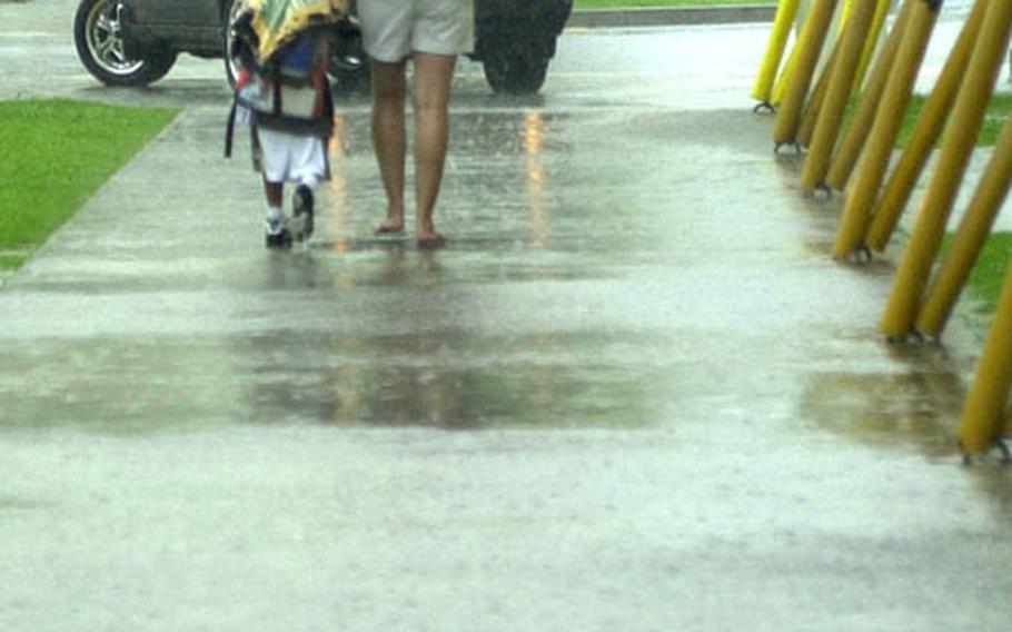 Veronica Ayala walks in the driving rain with her son, Anthony Kinder, a kindergartner at E.C. Killin Elementary School on Camp Foster, Sept. 19. She checked Anthony out of school early because of the incoming Typhoon Choi-Wan. Department of Defense Dependent Schools on Okinawa let out half-way through the day because of the weather.