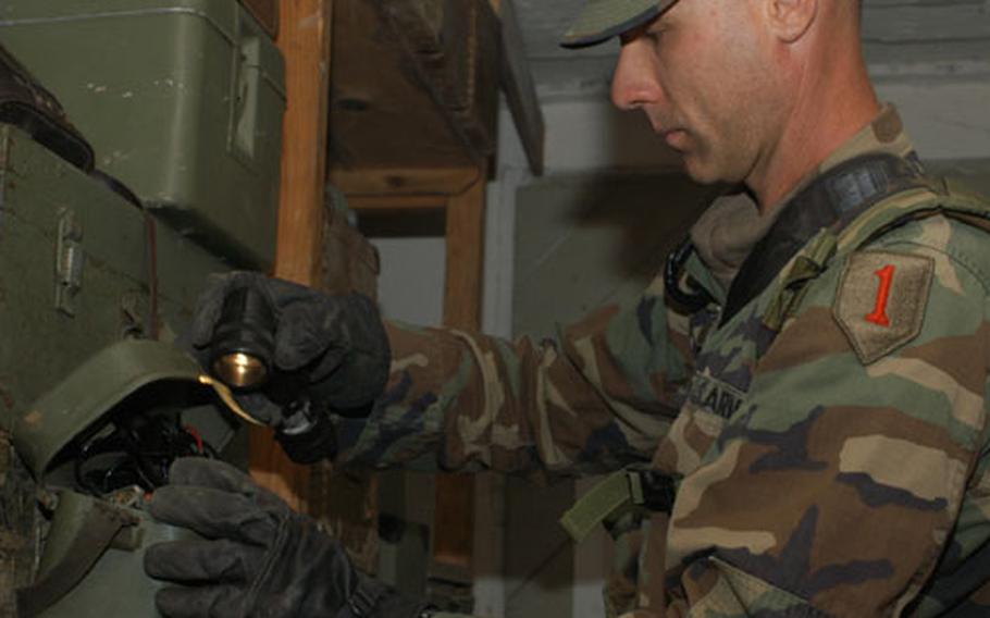 Spc. Kenny Santee of Task Force 1-18, a part of the 1st Infantry Division, uses a flashlight to search a box at the weapons storage site at a military camp at Manjaca Range during one of the Dynamic Response 03 exercises. Troops were checking to see if Bosnian Serb forces are in compliance with regulations on what type and amount of weapons and ammunition are authorized.