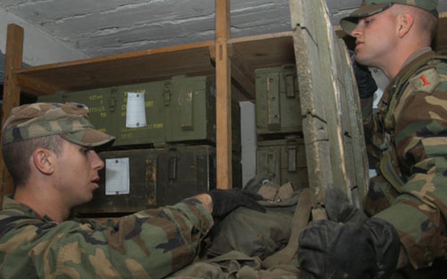 Spc. Andrew Shepherd, left, and Pvt. Steven Olson, both of Task Force 1-18, a part of the 1st Infantry Division, look through one of many boxes in the weapons storage site at a military camp at Manjaca Range during Dynamic Response 03 exercise. The task force deployed from Germany for three weeks. The purpose of the monthlong annual exercise in Bosnia and Kosovo is to show that coalition forces can rapidly deploy to the region to reinforce the international troops on ground if needed.