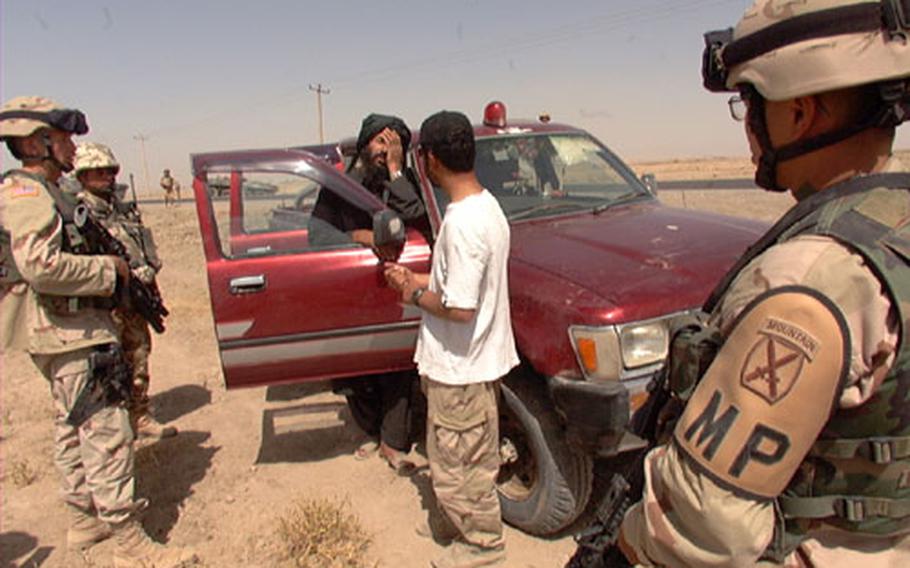 An Afghani tries to explain to military policemen why he was driving a government vehicle and had government papers Friday at a checkpoint manned by Romanian and American soldiers. The soldiers took photos of his identification cards and recorded telephone numbers from his satellite phone. The man’s identification turned out to be legitimate.