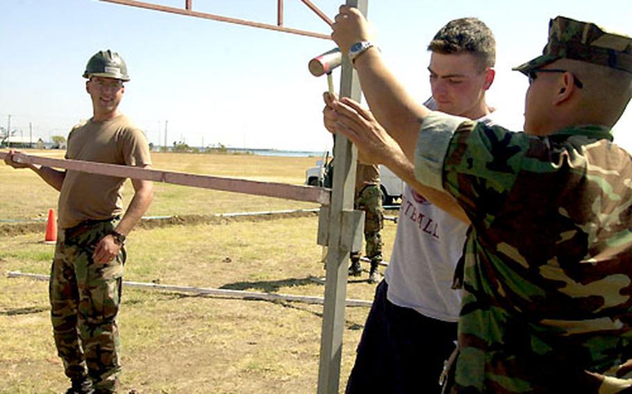 Petty Officer 1st Class Chris Szarek, left, Constructionman Robert Farrell, middle, and Petty Officer 2nd Class Joe Soriano, all Navy Seabees with Naval Station Rota Spain&#39;s Public Works Department, help put up the frame of a booth for the Naval Station Rota&#39;s 50th Anniversary celebration.