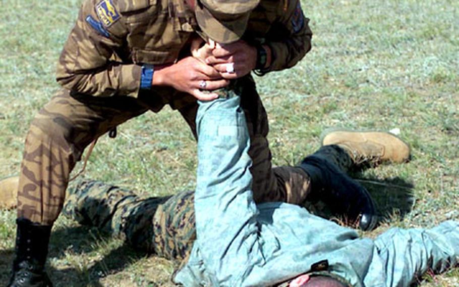 A Mongolian servicemember uses joint manipulation to control Sgt. Thomas Roussin, who played the role of a verbally and physically noncompliant person during a training exercise.
