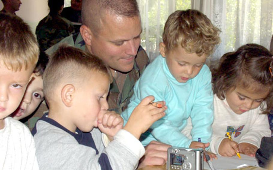 Capt. Joel Smith of the 414th Civil Affairs Battalion in Kosovo makes friends with Kosovar-Albanian children by coloring with them Tuesday. He helped the 628th Finance Detachment deliver toys and supplies to the children of the Our Future day care.
