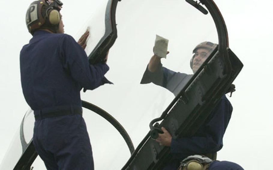 Airman Joey Zirnheld, let, and Airman Michael McDonagh wipe down the cockpit window as Airman Ashe Bridges, below, conducts final checks in the cockpit of an F-14 before its departure from Naval Air Facility Atsugi, Japan.