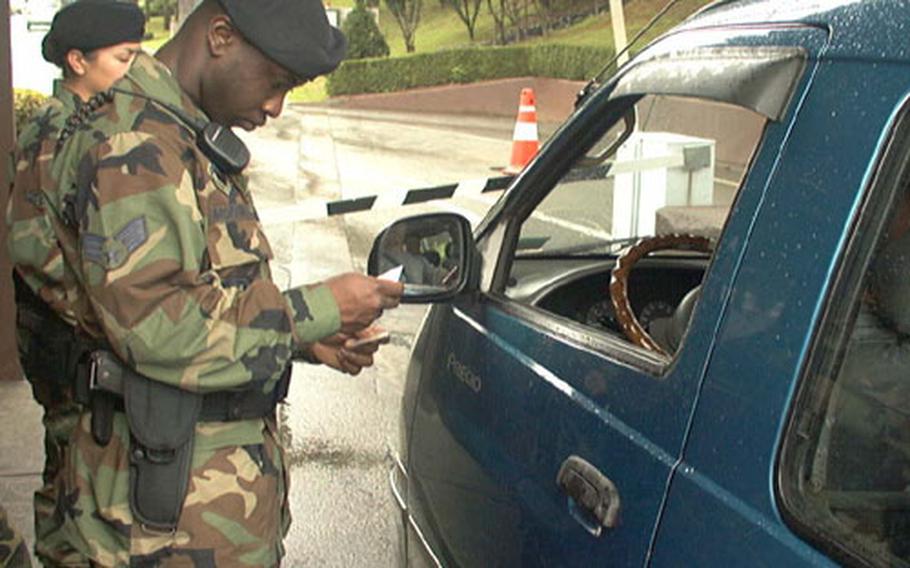 At Osan Air Base, South Korea, Senior Airman Samuel Morant of Fayetteville, N.C., a security forces airman, checks the ID card of a motorist seeking entry to base.