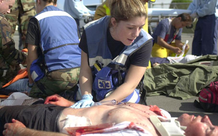 Airman Kristen Parker, from Kadena Air Base&#39;s 18th Aeromedical Dental Squadron, tends to a victim during the vehicle accident portion of Torii Station&#39;s annual mass casualty exercise.