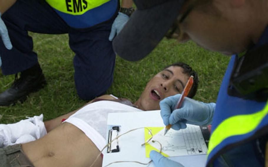 A victim of the mock helicopter crash at Landing Zone Renegade on Torii Station moans in pain as a medical worker marks his injuries on a tag. Torii Station held their annual mass casualty exercise Sept. 26 with local firefighters from Nirai and the other branches of U.S. service.
