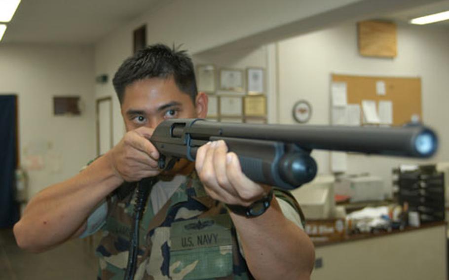 Petty Officer First Class Alexander Lamis, a Master-at-Arms at Naval Air Facility Atsugi, trains his modified shotgun on a suspect in a simulated scenario on a video screen as part of the Navy&#39;s Firearms Training Simulator, a new training device.