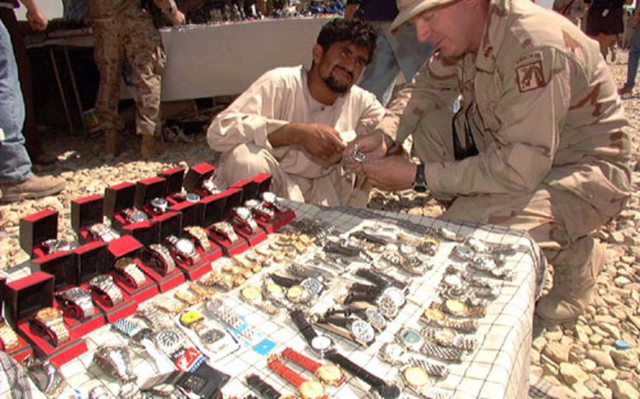 Capt. Charlie Brecken, from Coalition Joint Task Force 180’s signal section, checks out a variety of watches Friday at the weekly Bagram air base bazaar.