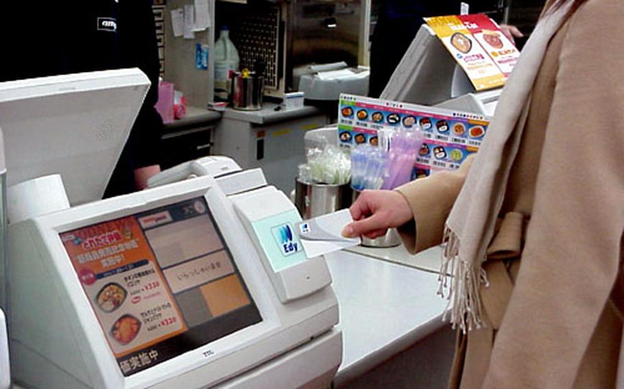 A shopper uses an Edy card to make a purchase at a convenience store.