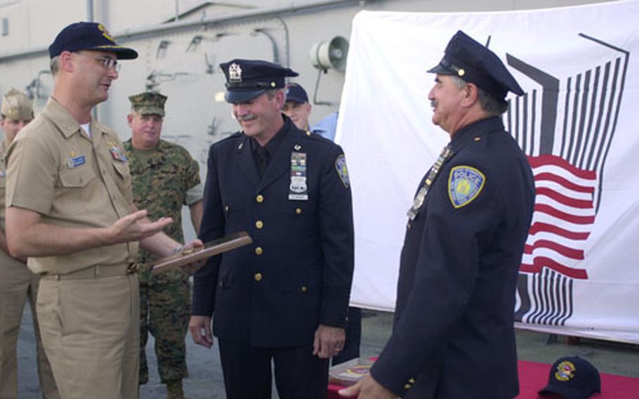 Navy Capt. Richard Landolt, left, Commodore of Amphibious Squadron 11, talks with New York City Port Authority police officers Barry Pikaard, center, and John Zultanky, right, as he presents them with a plaque aboard the USS Essex. Pikaard and Zultanky presented the Navy and Marine Corps with an American and World Trade Center flag in remembrance of the victims of the Sept. 11, 2001, terrorist attacks.