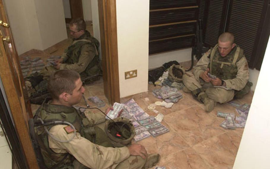 Spc. Shawn Re, right, Sgt. Clarence Skillin, left, and Pfc. Patrick Traphagan, back, counted bags of Iraqi money found in a raid last Wednesday at a mansion south of Baghdad. The raid turned up a few weapons, money and lots of clues, but not the No. 15 man on the U.S. most-wanted list.