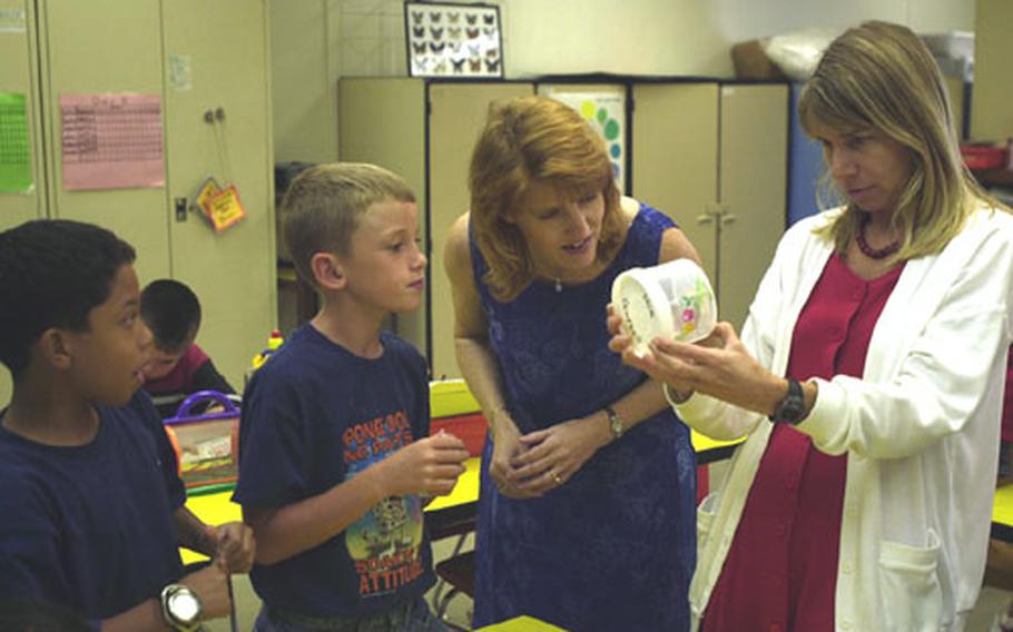 Department of Defense Dependents Schools&#39; Okinawa District Teacher of the Year Karin Mordt, center, looks at a bug that Art Teacher Chrisse Harwanko is holding while students Anthony Grantham, left, and Jacob Newton look on.