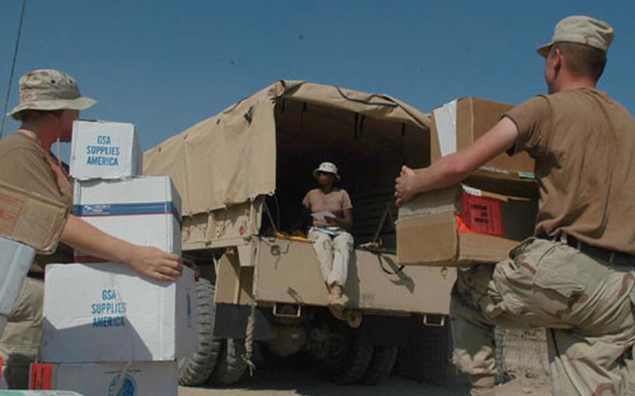 Spec. Suzanne Myers, left, and Sgt. Joseph Turner pick up boxes to carry into the 541st Corps Support Battalion&#39;s Tactical Operations Center as Sgt. Crystal Brown sorts letter mail. All three are members of the U.S. Army Reserve&#39;s 79th Quartermaster Company at Logistics Base Seitz, located a few hundred yards north of the Baghdad International Airport perimeter. The battalion is made up of reserve, National Guard and regular Army troops.