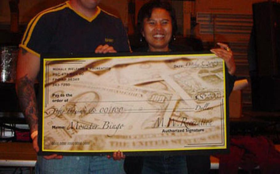 Charles Dry and Pramchit Martinson accept their ceremonial check for $50,000 at Yokosuka&#39;s Morale Welfare and Recreation Monster Bingo Game, Sunday Oct. 5, 2003. More than $110,000 in cash prizes were awarded Sunday, at Yokosuka Naval Base&#39;s Thew Gym. Dry and Martinson will each get $25,000 before taxes.