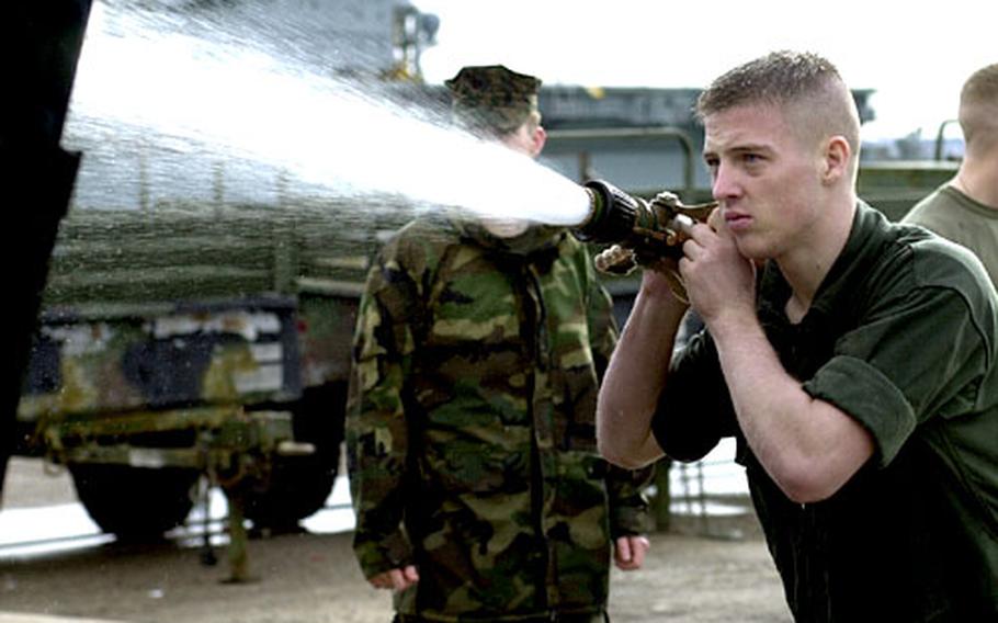 Marine Cpl. William Hoornstra fires a high-powered hose at a truck Tuesday at Rota. About 5,000 sailors and Marines with the Iwo Jima Amphibious Ready Group are in Spain to wash down equipment, paint their ships and get some rest and relaxation before heading home after an 8-month deployment.