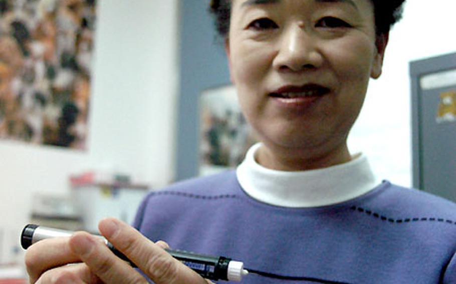 Kazuko Fujieda, diabetes nurse at Yokosuka Naval Hospital, Japan, holds a new portable insulin pen. The device is offered to insulin-dependent diabetics. The hospital has more than 500 diabetic patients, and staffers have begun to implement a new program that seeks to better serve their needs.