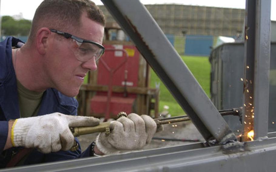 Sergeant Jeremey Powell, a member of Team LAR from 4th Light Armored Reconnaissance Battalion, cuts a piece of metal that his team will use to build their vehicle in the Recycle Wars.
