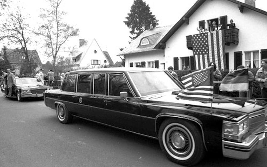 President Reagan&#39;s motorcade passes a house bedecked with a large American flag at Bitburg.