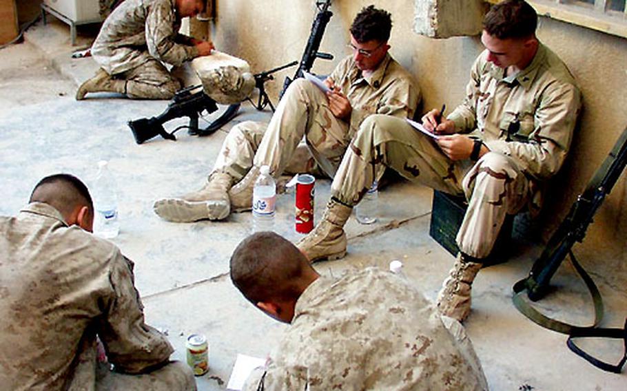 Marines put down their weapons and fill out survey forms for Stars and Stripes reporters in Iraq.