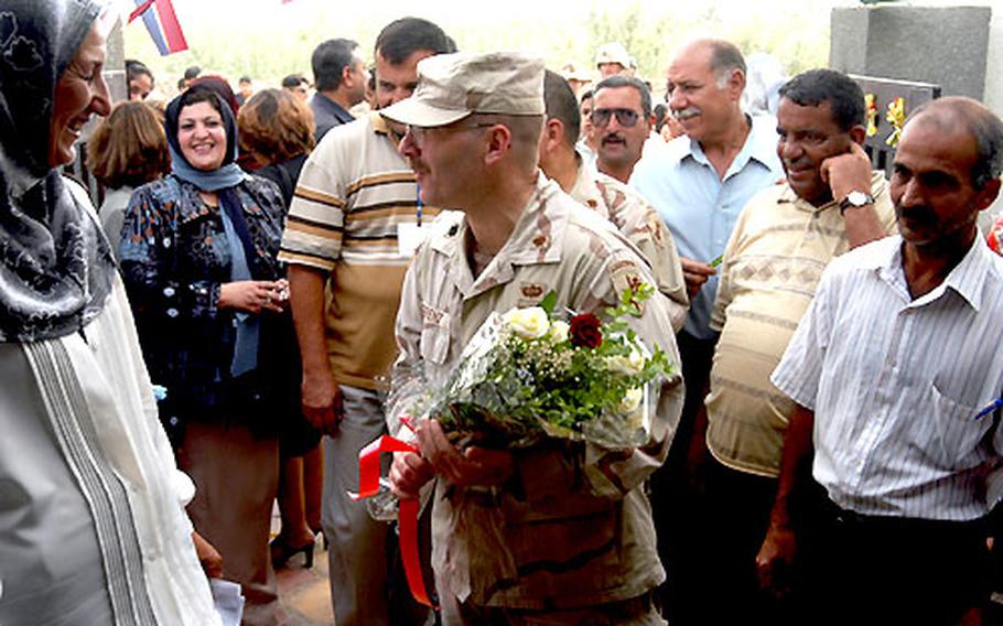 Lt. Col. Jim Berenz of the 308th Civil Affairs Brigade carries flowers handed to him Sunday as he enters the primary school in the French Quarter of Baghdad.