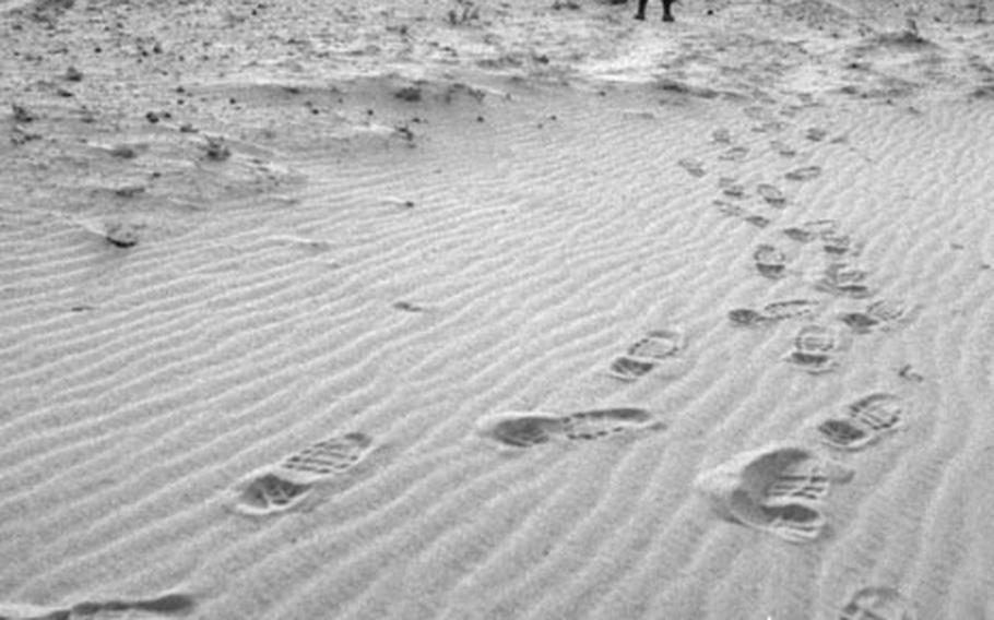 Soldiers' footprints interrupt wind-created ripples in the desert sand in Saudi Arabia in 1990.