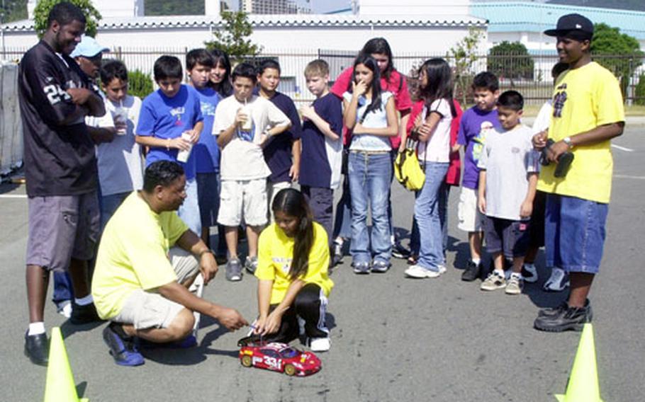 Lloyd Buster, Sasebo Naval Base&#39;s MWR assistant director of youth activities, and Vanny Angeles, 11, prepare an Extreme Teams pace car for a dash around the parking lot at the Hario Housing Village Chapel last weekend.