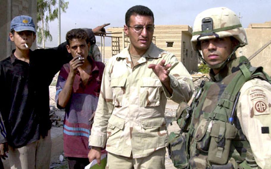 A coalition interpreter, center, talks with Sgt. 1st Class David Santos in August. Santos and the interpreter had stopped to talk to a group of homeless boys, pictured to the left, in Baghdad.