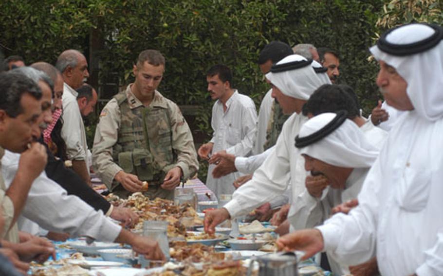 Capt. Matthew Cunningham, commander of Company A, 1st Battalion, 8th Infantry Regiment in Iraq shares a meal Friday with several locals at the home of a local shiek. The meal was served "family style" in the garden, under the grapefruit trees. The shiek invited military members stationed nearby as a sign of friendship.