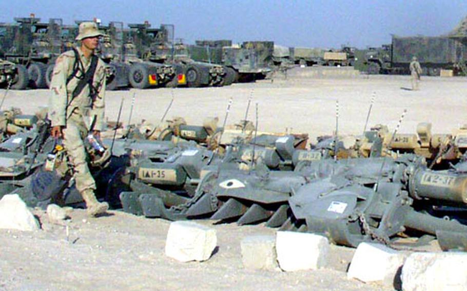 A soldier walks by tank attachments used to clear land mines at Camp Dogwood, south of Baghdad. Though living conditions in Iraq are expected to improve greatly as time passes, many troops are concerned with deeper issues. Decisions made by the leaders of the armed forces on issues such as length of deployment and troop rotations will do more to decide the experience of servicemembers in Iraq than anything else, both troops and observers say.