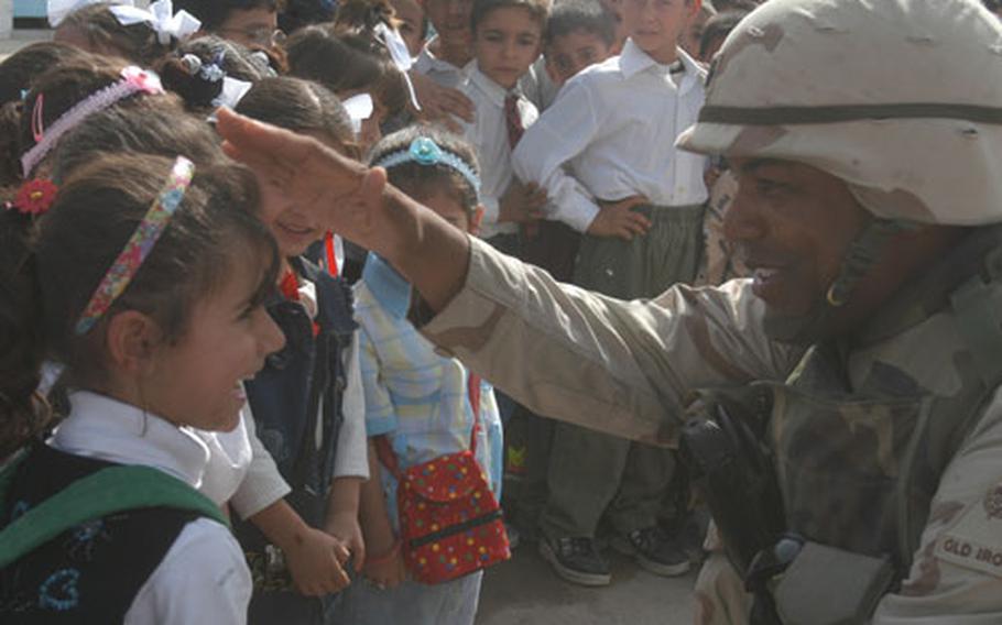 Lt. Col. Chuck Williams, commander of 1st Squadron, 1st Cavalry Regiment of the 1st Armored Division, greets a young admirer Monday at a school opening in a Baghdad neighborhood.