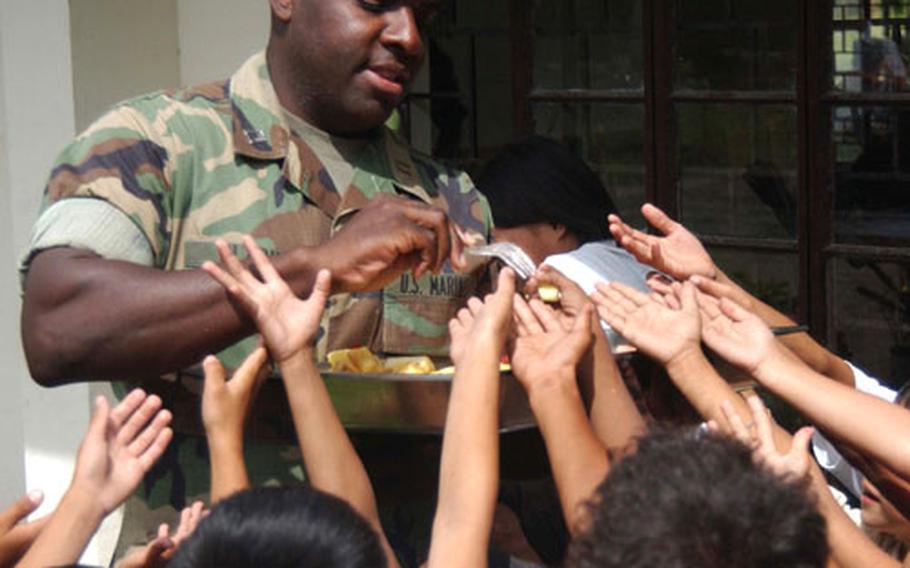 Children recieve fresh fruit from Capt. Earl Clark, intelligence officer, Marine Aircraft Group-36, 1st Marine Aircraft Wing, after a cornerstone ceremony for a new school building, community center and recreational facilities in Capas, Tarlac. The Okinawa-based Marines are in the Phillipines for Talon Vision, a two-week training exercise with Philippine forces.