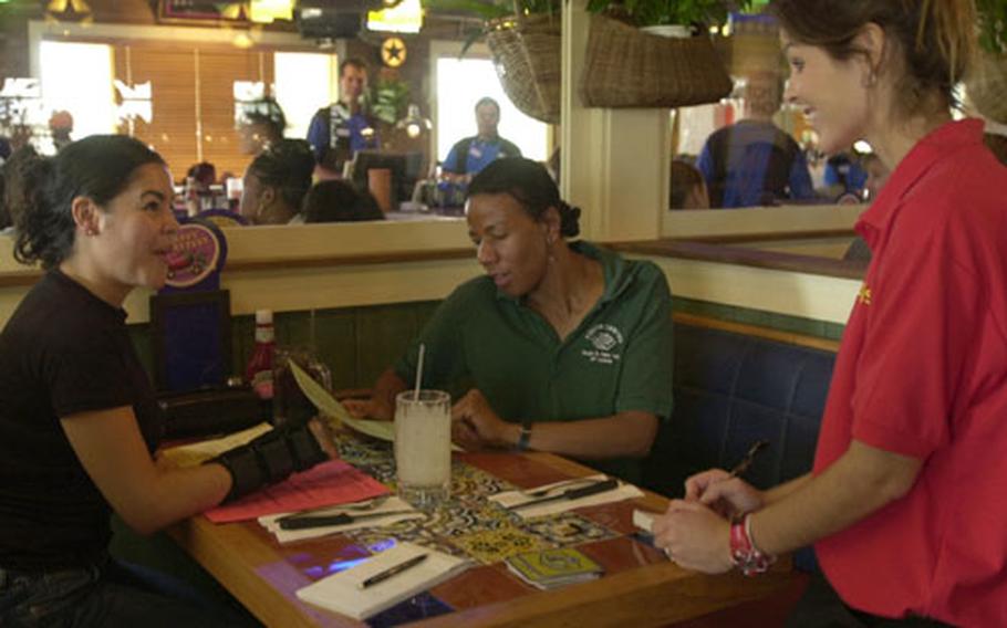 Air Force Staff Sgt. Evelyn Sosatoledo, left, can hardly contain her excitement as she orders her favorite, baby back ribs, from server Adrienne McClay at the new Chili&#39;s on Kadena Air Base. Tech. Sgt. Juanita Brooks, center, received a ticket getting herself and Sosatoledo into the restaraunt for the free tasting Friday.
