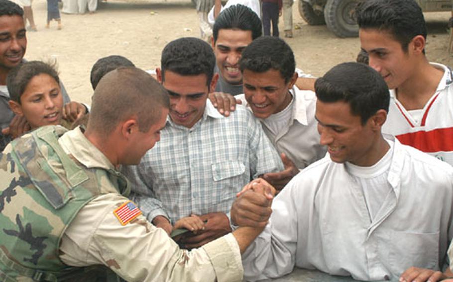 Spc. Sean Raby of the 1st Battalion, 152nd Infantry, arm wrestles an Iraqi man from the village of al-Jawdia on the hood of a humvee as members of the 161st Area Support Medical Battalion provided medical support to villagers in the nearby clinic. Raby lost the match, but chalked it up to improper technique on the Iraqi&#39;s part.