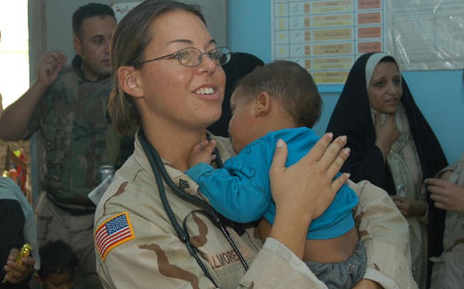 Sgt. Christy Fillmore holds a young Iraqi baby as the child&#39;s mother receives medical care in the village of al-Jawdia, Iraq.