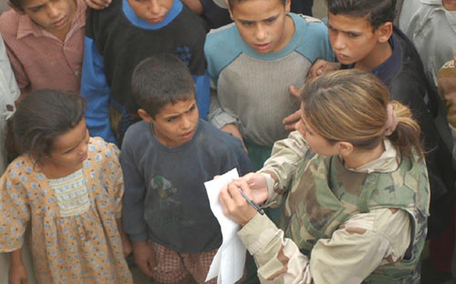 Translator Holly Saco of Sterling Heights, Mich., writes down the names of Iraqis wanting medical care at the al-Jawdia, Iraq, clinic. The town&#39;s children were ever-present, crowding in to watch whatever a soldier or civilian was doing.