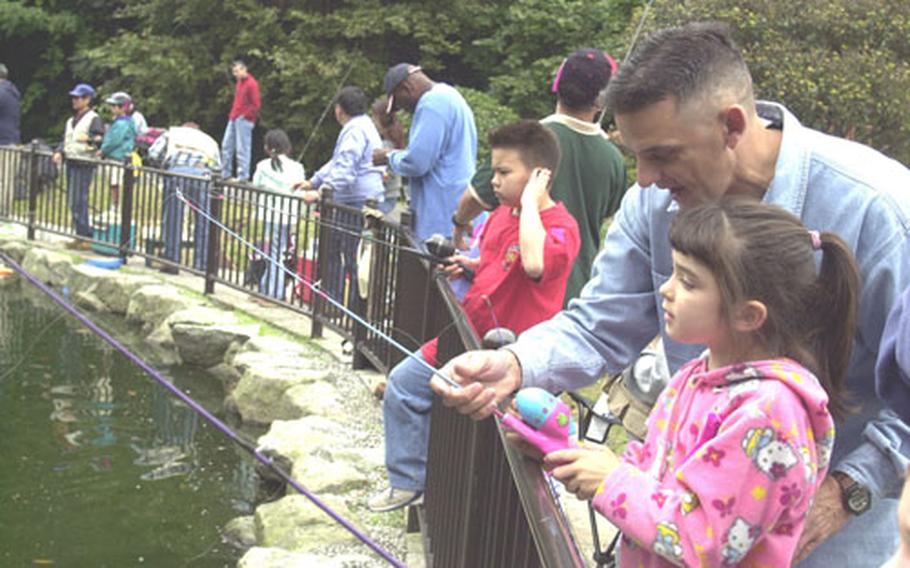 Army Sgt. Maj. Darrel Calton gives his daughter, Kaylin, fisherman technique pointers during Camp Zama&#39;s fishing derby at Dewey Park Pond on Saturday.