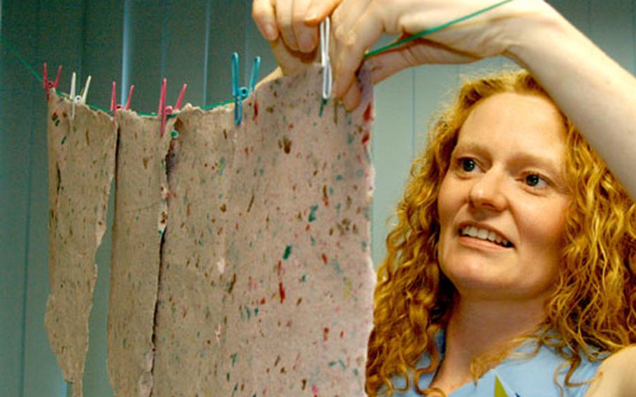 Sixth-grade teacher Kina Stallings hangs up pink speckled paper sheets to dry Thursday at Heidelberg Middle School.