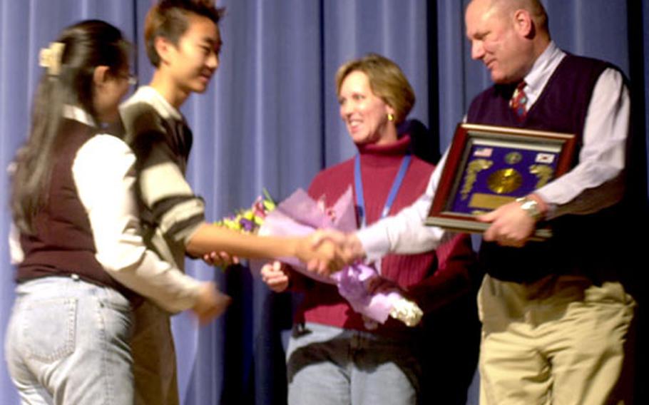 Korea schools superintendent Bruce W. Jeter and his wife, Linda, accept a plaque Monday during an honors assembly at Seoul American High School. Jeter will leave Korea Dec. 20; his replacement has not been named.