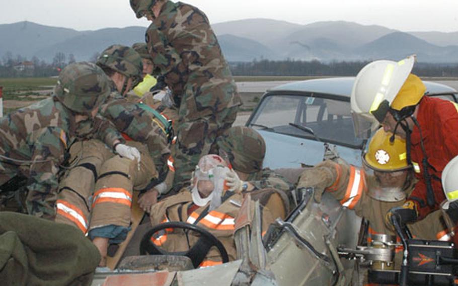 Using the Jaws of Life, firefighters cut the car door to free a trapped car accident victim while Task Force Med Eagle medics extract the passenger during a joint exercise on Saturday at Eagle Base, Bosnia and Herzegovina.