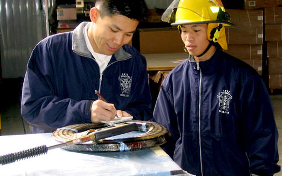 Chief Dispatcher Takahiko Tsutsui scans through some instructions with Firfighter Ryoichi Fujita in preparation for the grand opening.