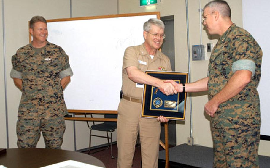 Col. Chuck Dallachie, right, commanding officer of the 3rd Material Readiness Battalion, accepts the 2003 Command Award of Excellence from Capt. Dale Molé, executive officer of the U.S. Naval Hospital Okinawa, while Petty Officer 1st Class Stuart Satter, 3rd MRB, looks on. The unit received the award for their efforts in supporting the Armed Services Blood Bank Center with at least one blood drive a month.